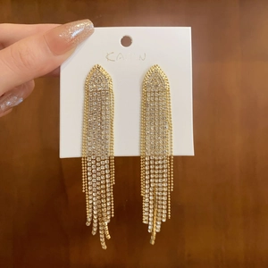 Detail of long gold tassel earrings featuring sparkling zircon fringe and triangle tops