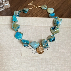 Detailed shot of irregular turquoise shell beads with a golden seashell pendant