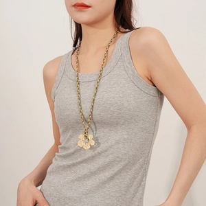 Detailed close-up of a golden flower pendant with hammered texture and woven cord chain