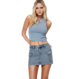 Ensemble élégant mini-jupe cargo en jean délavé et débardeur dos nu sur fond blanc