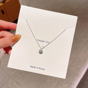 Close-up of a silver titanium steel necklace with a zircon pendant on a display card