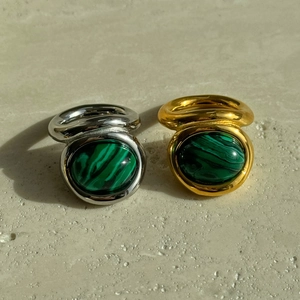 Detailed view of vintage gold and silver rings with oval malachite stones on stone background