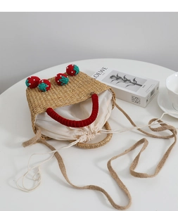 Détail du sac en paille fait main avec breloques fraises et poignée en velours rouge
