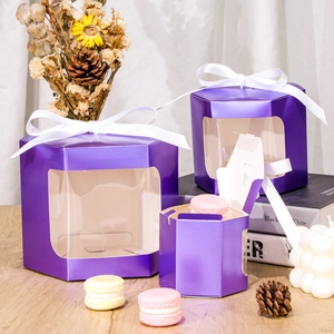 Three sizes of purple hexagonal laser-cut gift boxes with ribbons on a wooden background
