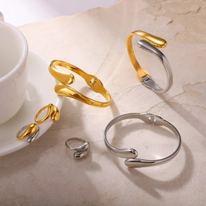Macro detail of teardrop-shaped stainless steel bangles and rings set in gold and silver