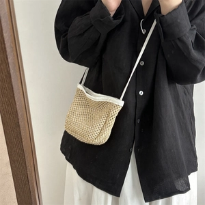 Borsa a secchiello in paglia intrecciata da donna indossata da modella con camicia di lino