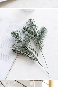 Detailed close-up of grey-green artificial pine needles on white marble surface