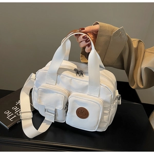 Detail der weißen Nylon-Handtasche mit Vordertaschen und brauner kreisförmiger Verzierung