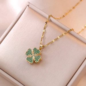 Elegant gold four-leaf clover necklace featuring green rhinestones on a jewelry box