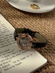 Detail of rose gold quartz watch with rhinestone bezel on an open book background