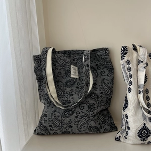 Detailed close-up of retro paisley print and ethnic floral embroidery on linen tote bags