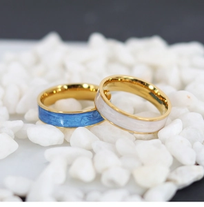 Detail of gold-plated rings featuring blue and white marble enamel textures on pebbles