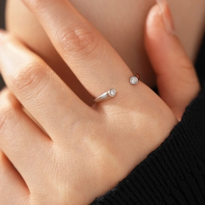 Gros plan d'une bague ouverte en argent avec deux zircons blancs sur un doigt
