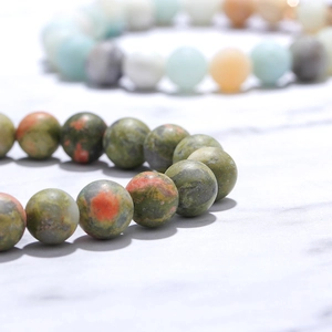 Lava stone bead bracelet set for best friends with engraved charms on marble background