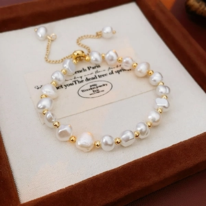 Detail of adjustable pearl bracelet with golden beads on a jewelry display tray
