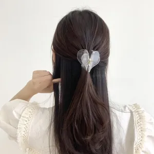 Detail view of heart-shaped transparent hair claw clip in a chic half-up hairstyle