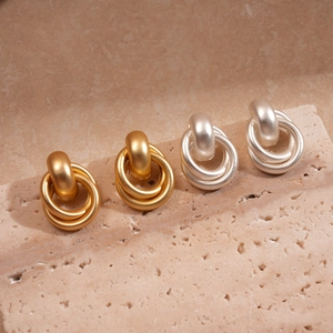 Boucles d'oreilles géométriques mates dorées et argentées sur un socle en pierre