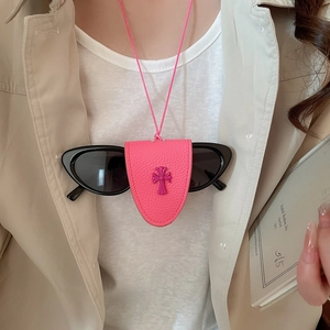 Pink leather glasses holder necklace with cross emblem worn over a beige coat