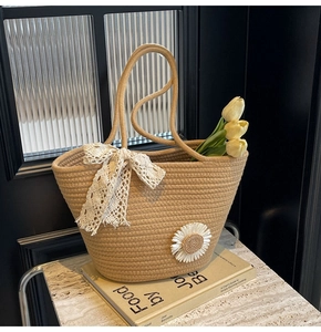 Detail of straw tote bag featuring white lace bow and daisy floral ornament