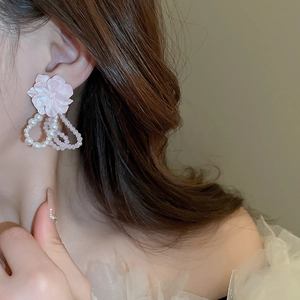 Gros plan de boucles d'oreilles fleurs en acrylique rose avec perles sur un modèle
