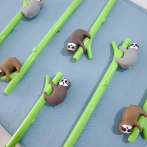 Close-up of creative green bamboo-shaped pens featuring cute silicone sloth figurines