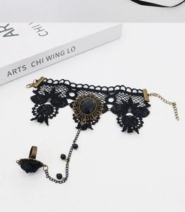 Detail of gothic black lace finger bracelet with antique bronze ring and dark gemstone