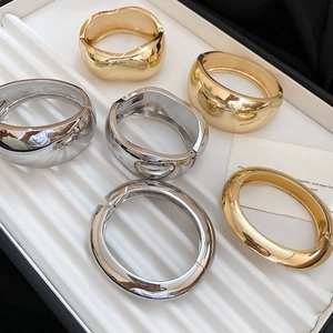 Detailed view of chunky gold and silver geometric bangles on a jewelry tray