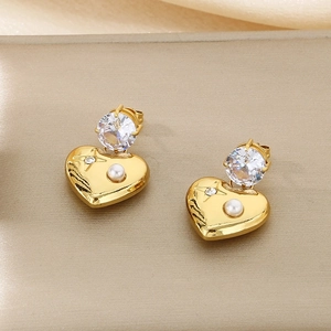 Detailed close-up of 18K gold heart earrings featuring white pearls and cubic zirconia stones
