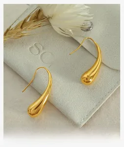 Polished golden teardrop earrings on a velvet pouch with elegant dried flower accents