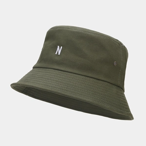 Détail macro de la lettre N brodée en blanc et des coutures renforcées sur le chapeau vert