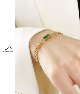 Detail of gold-plated stainless steel chain bracelet with a green rectangle gemstone