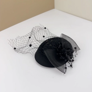 Detail of a vintage black fascinator hat with polka dot mesh veil and floral beads