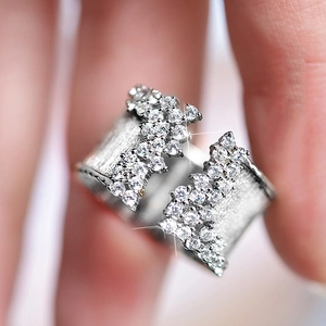 Macro shot of silver wide ring with brushed texture and sparkling zircon inlay