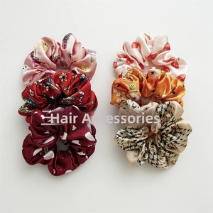 Detailed view of six patterned satin scrunchies in polka dot, floral, and strawberry prints