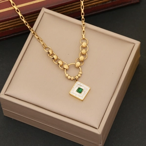 Detail of a square gold pendant featuring a green gemstone and sparkling diamond accents