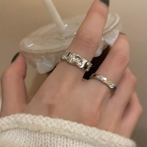 Detail of silver irregular textured rings with hammer-finish on a hand in an ins-style setting