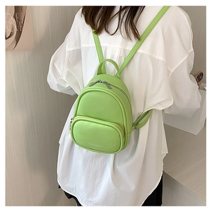 Rear view of a model wearing the green mini PU leather backpack with adjustable straps