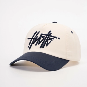 Detail shot of navy HUSTLE 3D embroidery on a cream and navy blue baseball cap
