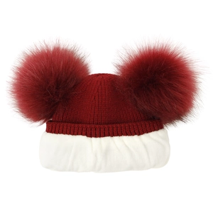 Close-up of red knitted winter hat with double faux fur pom-poms and fleece lining