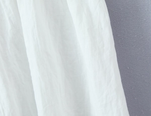 Dettaglio del tessuto di cotone bianco e lino con texture naturale e pieghe morbide