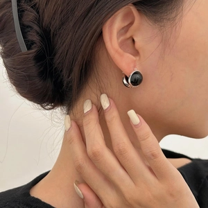 Close-up of minimalist silver hoop earring with black agate gemstone on model