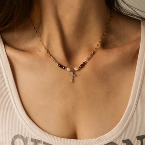 Golden cross necklace with freshwater pearls and zircon accents on a model's neck