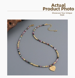 Detail of beaded necklace featuring colorful stones and gold heart eye totem pendant