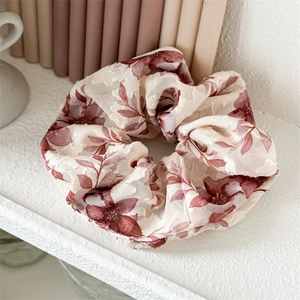 Detail of floral chiffon hair scrunchie with burgundy flowers on beige fabric background