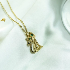 Detail view of a hollow golden cat pendant with green gemstone eyes on white silk fabric