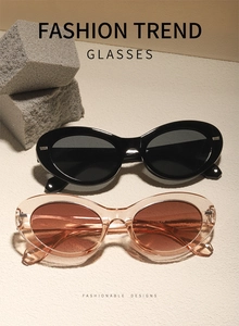 Detail view of retro oval sunglasses in black and tea colors on natural stone surface