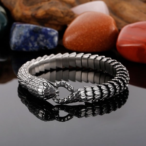 Detailed close-up of snake scale textured metal bracelet with dragon clasp on black surface