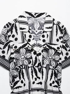 Detail of tropical floral print on black and white Cuban collar romper with chest pockets
