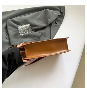 Detailansicht der braunen Ledertasche mit Seitenstruktur und glatten Kantennähten