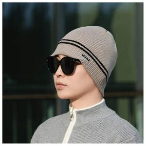 Close-up of beige knit beanie showing vertical ribbed texture and FBQE logo label